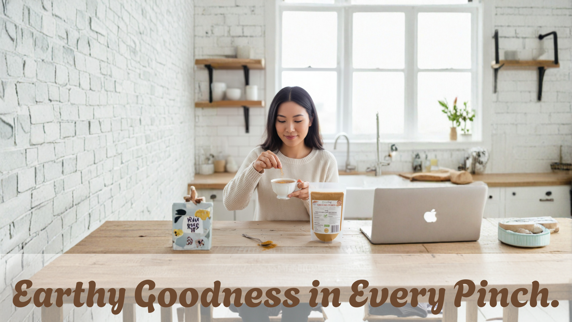 Woman in a kitchen using a laptop with a bowl and containers on the table, text 'Earthy Goodness in Every Pinch' below.