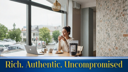 Woman sitting at a table with a laptop, drinking coffee, in a cafe with a view of the street.