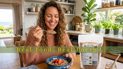 Woman eating cereal with a bowl of strawberries in a kitchen, with a package of oats in the foreground.