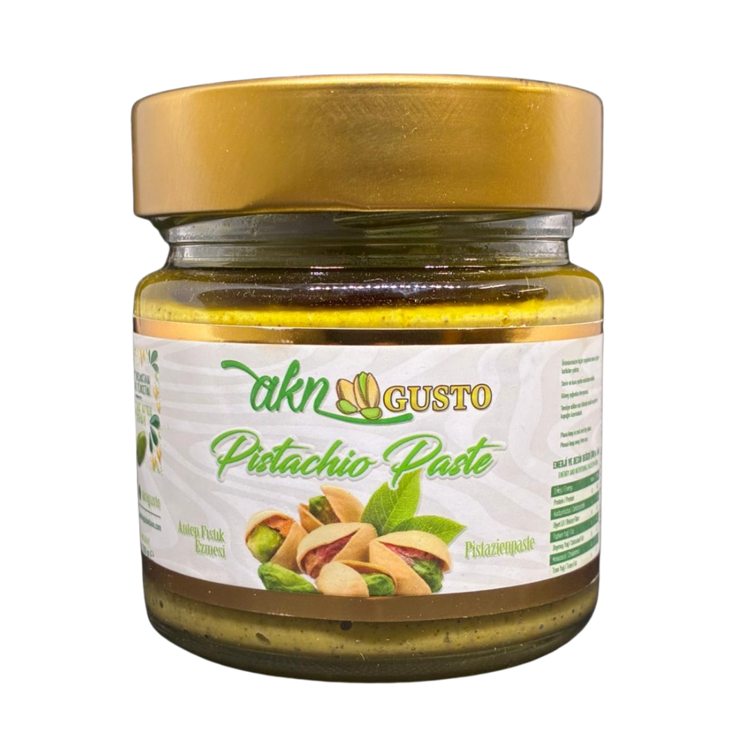 Jar of pistachio paste with a gold lid on a white background