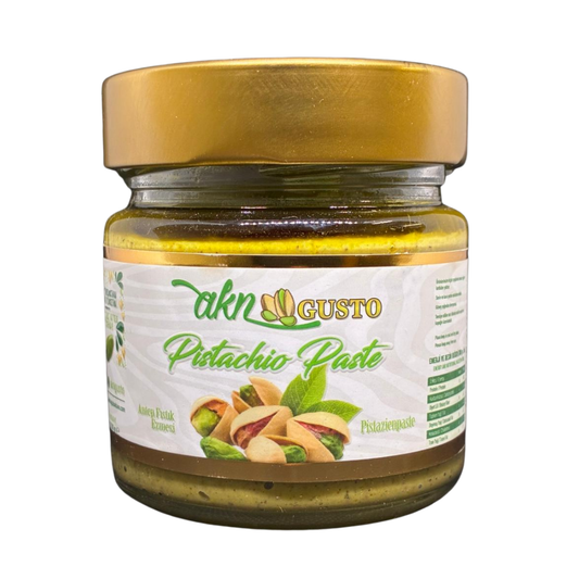 Jar of pistachio paste with a gold lid on a white background